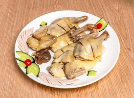 Lung Guang Chicken Whole poached chicken cut with cucumber served in tray dish isolated on wooden table side view of hong kong food photo