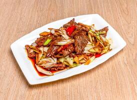 Stir fried beef and welsh onions served in tray dish isolated on wooden table side view of hong kong food photo