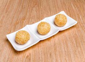 Fried Dumplings balls and Quicksand topped with sesame seeds served in tray dish isolated on wooden table side view of hong kong food photo