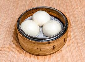 Quicksand Custard Bun served in bamboo steamer isolated on wooden table side view of hong kong food photo