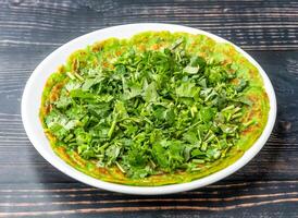 Savory Spinach Pancake topped with coriander served in dish plate isolated on wooden table side view of hong kong food photo