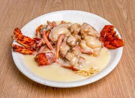 Baked Lobster with Cantonese Egg Noodles sauce served in broth dish isolated on wooden table side view of hong kong food photo
