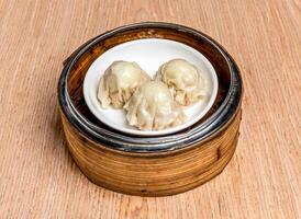 Quail Egg Siomai served in bamboo steamer isolated on wooden table side view of hong kong food photo