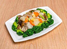 Stir fried Scallops with Greens including broccoli, tomato and scallions served in tray dish isolated on wooden table side view of hong kong food photo