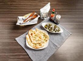 Palak Paneer with Naan with chilli garlic sauce served in plate isolated on napkin side view of pakistani and indian spices on wooden background photo