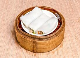 steamed Chicken noodle rolls served in bamboo steamer isolated on wooden table side view of hong kong food photo