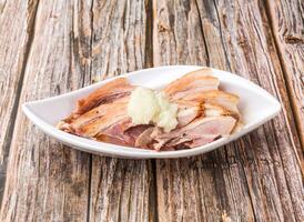 Garlic smoked pork trotter topped with garlic paste served in dish isolated on wooden table side view of hong kong food photo