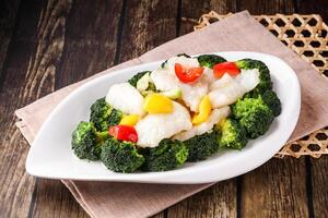 Sauteed Broccoli Balls with steamed fish, tomato and green onion served in dish isolated napkin side view of hong kong food on wooden background photo