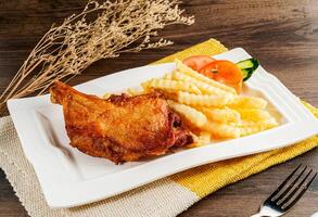 Fried chicken with French fries and salad served on tray dish isolated on napkin side view of hong kong food on wooden table photo