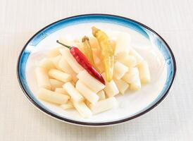 Spicy and Sour Lotus Root Tips with red chillies served in bowl isolated on white background side view of hong kong food photo