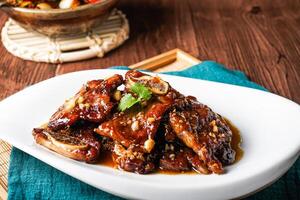 Braised Beef Short Ribs with Garlic Sauce served in tray dish isolated on napkin closeup side view of hong kong food on wooden table photo