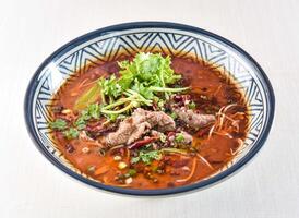 Sichuan Boiled beef topped with red pepper, coriander and green onion served in bowl isolated on white background side view of hong kong food photo