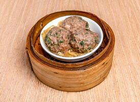Fresh Bamboo Beef Balls served in bamboo steamer isolated on wooden table side view of hong kong food photo