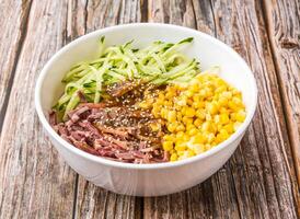 smoked hoof shreds cold shaved noodles including chilled noodles, shredded cucumbers, and sweet corn kernels served in bowl isolated on wooden table side view of hong kong food photo