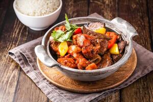 Pork Belly and Pork Ribs Stew with Steamed Rice served in broth isolated on napkin side view of hong kong food on wooden background photo