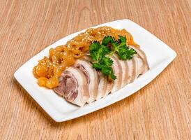 Jellyfish and chilled sliced Pork trotter topped with sesame seeds and coriander served in tray dish isolated on wooden table side view of hong kong food photo