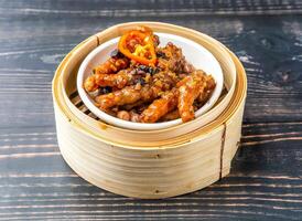 Braised Chicken Feet with Black Bean Sauce served in bamboo steamer isolated on wooden table side view of hong kong food photo