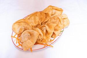 Fried Wonton garnished with carrot slice served on white plate isolated on white background top view of thai and bangladeshi food photo