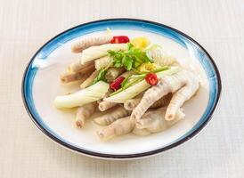 Pickled pepper chicken feet with coriander served in bowl isolated on white background side view of hong kong food photo
