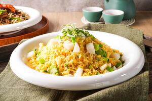 Golden Seafood Fried Rice and Scallops served on plate with a teapot and teacups in the background side view of hong kong food photo
