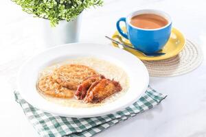 noodles soup with meat and chicken wings served in plate with a cup of hot milk tea isolated on white background side view of hong kong breakfast or brunch photo