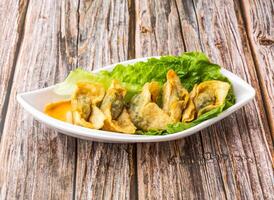 Crispy Fried Wontons with lettuce leaves served in dish isolated on wooden table side view of hong kong food photo