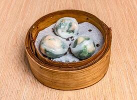 Steamed Shrimp and vegetable dumplings served in bamboo steamer isolated on wooden table side view of hong kong food photo