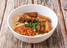 Dongpo Pork sliced Noodles eith sauce and scallions served in bowl isolated on wooden table side view of hong kong food photo