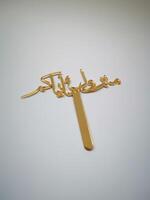 Gold Arabic Calligraphy Cake Topper perfect for adding a festive touch to any birthday cake topper is made of a durable material and features elegant calligraphy isolated on white background top view photo