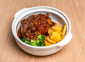 Braised Pork trotter with black pepper casserole, broccoli and wedges served in broth dish isolated on wooden table side view of hong kong food photo