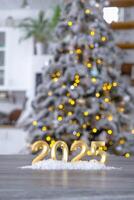 Golden figures number 2025 New Year against the background of tiny house with warm light and garlands. Greeting card, Happy New Year, cozy home photo