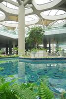 a large indoor pool with plants and a glass ceiling at the new yogyakarta international airport photo
