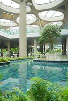 a large indoor pool with plants and a glass ceiling at the new yogyakarta international airport photo