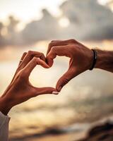 Couple making heart shape with hands on beach photo
