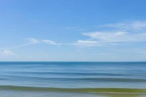 Motion of the wave on the beach with blue sky and clouds. photo