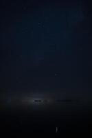 Vertical image of Stardust in the night with noise and grain on the sky with soft light of city in bottom photo
