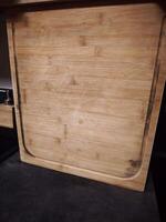 Used bamboo cutting board showing signs of wear and tear in kitchen setting photo