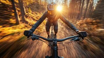 Mountain biker riding fast on trail at sunset in autumn forest photo