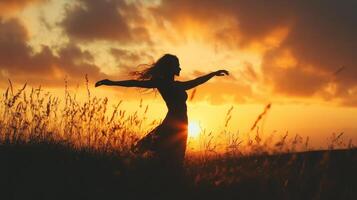 Young woman dancing in a field at sunset, feeling free and happy photo