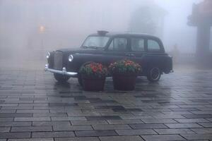 A Vintage Car on a wet street in Foggy Urban Setting photo