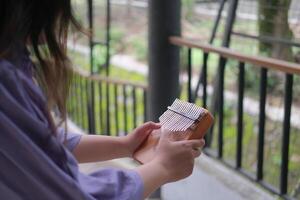 woman playing a kalimba in a vibrant park filled with green leaves on a warm summer day photo