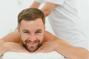 Handsome middle-aged man enjoying relaxing spa massage with oils photo