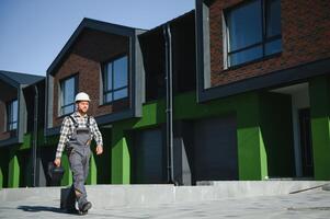 Master on call. A plumber or builder is standing near a house. photo