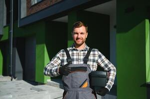 Master on call. A plumber or builder is standing near a house. photo