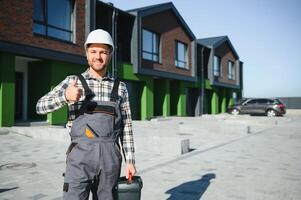 Master on call. A plumber or builder is standing near a house. photo