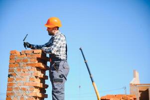 Installing brick wall. Construction worker in uniform and safety equipment have job on building photo