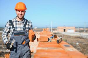 Installing brick wall. Construction worker in uniform and safety equipment have job on building photo