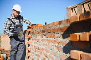 Installing brick wall. Construction worker in uniform and safety equipment have job on building photo