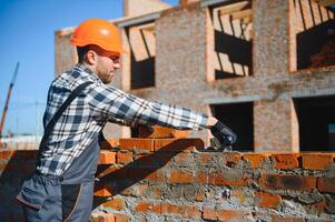 Installing brick wall. Construction worker in uniform and safety equipment have job on building photo