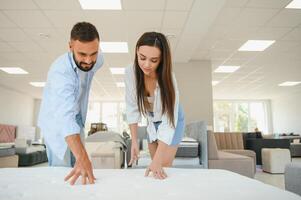 A young couple is choosing bedding at a bed, mattress and pillow store. Everything for a comfortable sleep photo